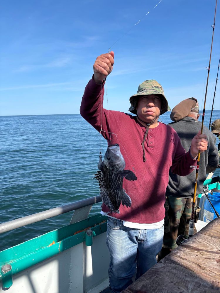 Person holding a fish on a boat with a blue ocean in the background.