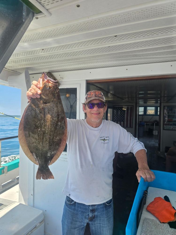 Person on a boat holds a large flat fish.