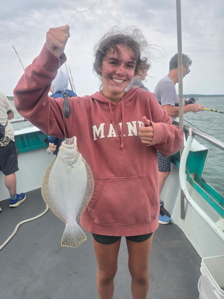 Person holding a fish on a boat, smiling with a thumbs-up.