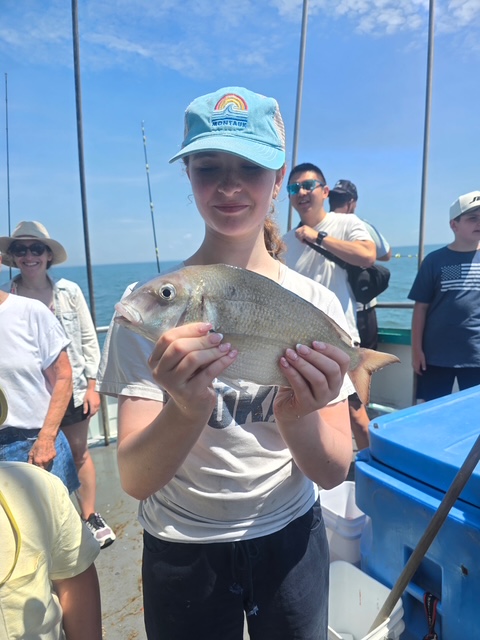 Person holding a fish on a boat with others in the background.