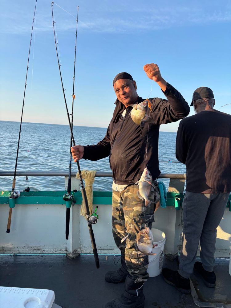 Man holding fishing rod with caught fish on a boat.