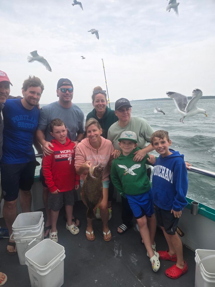Group on boat with fish, ocean and seagulls in background.