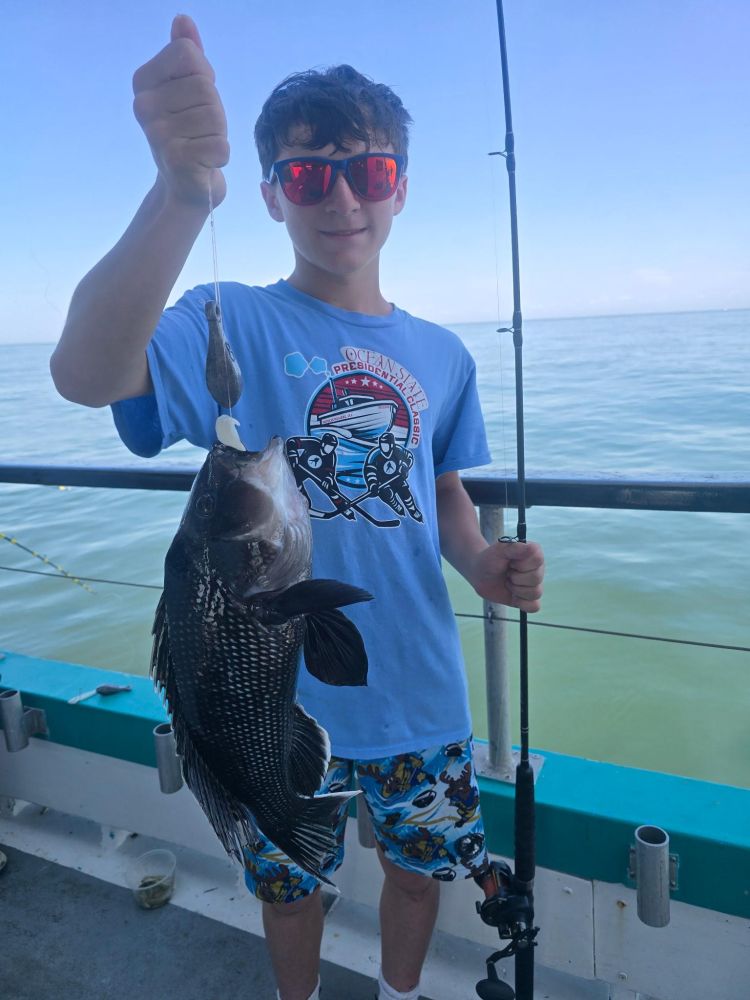Person holding a fishing rod with a fish on a boat.