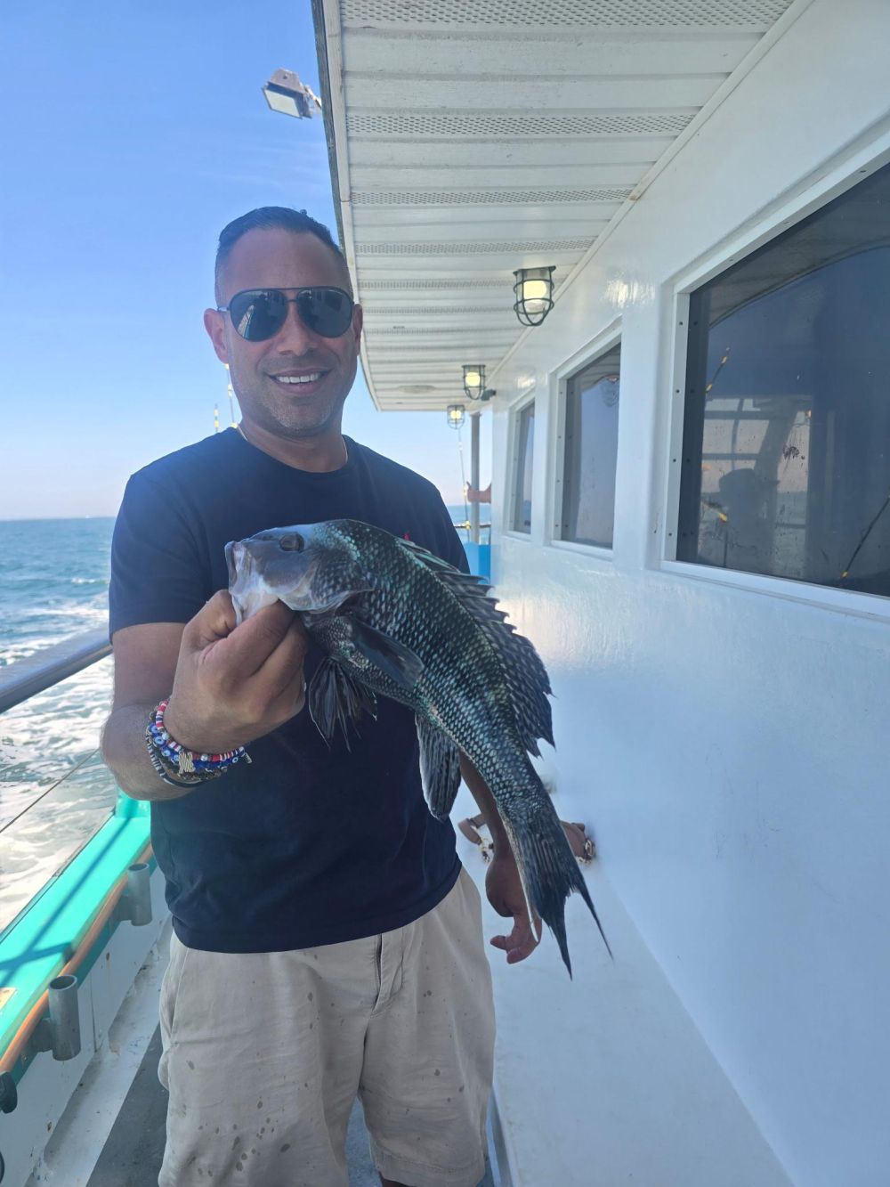 Person holding fish on a boat with ocean view.