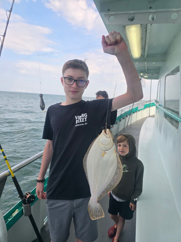 Person on a boat holding a fish, with another person in the background.