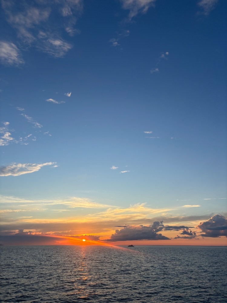 Sunset over the ocean with clouds in the sky.