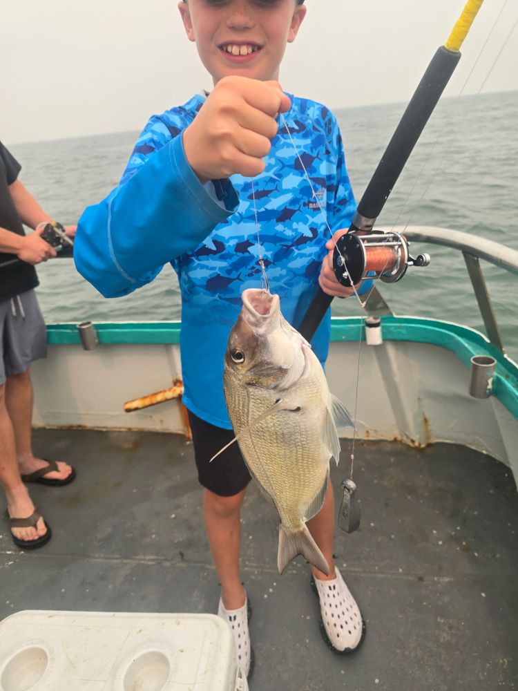 Child on boat holding a fish with a fishing rod.
