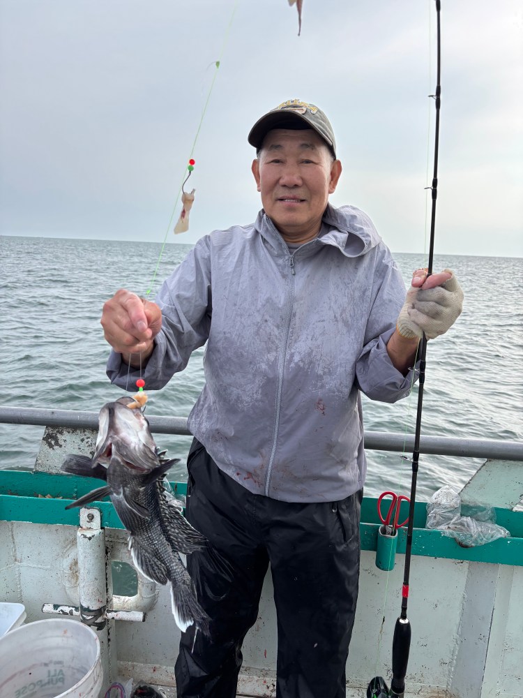 Man holding a fish on a boat with a fishing rod.