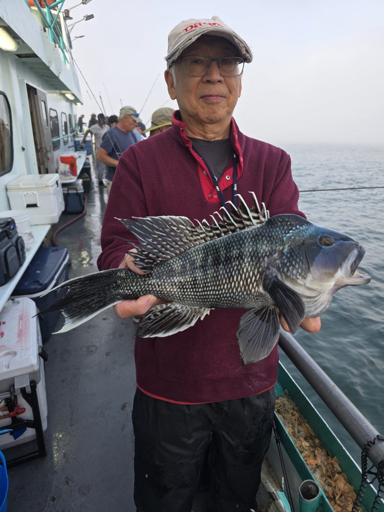 Person on a boat holding a large fish, with ocean in the background.