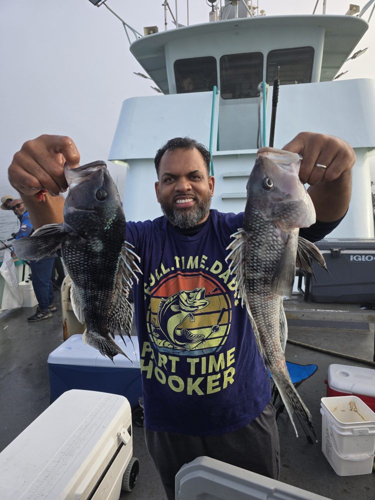 Person holding two fish on a boat, smiling.