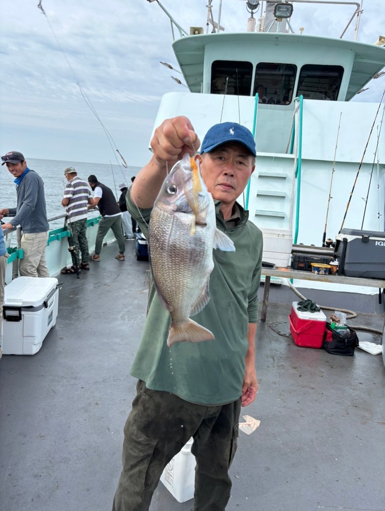 Man holding a fish on a boat with people in the background.