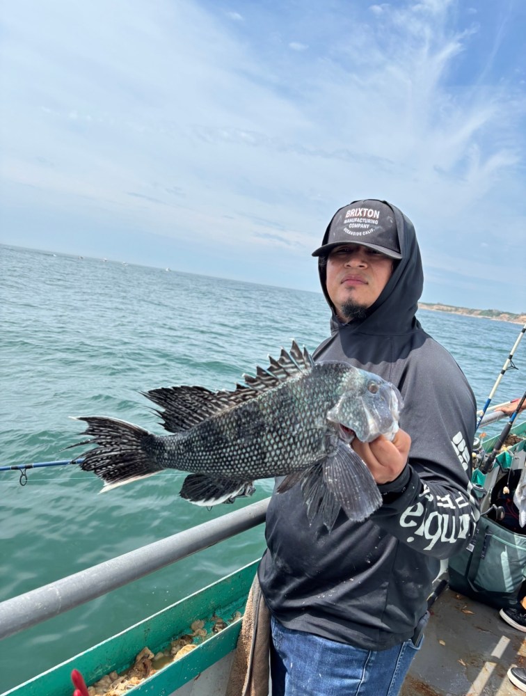 Person on boat holding a large fish with ocean in the background.