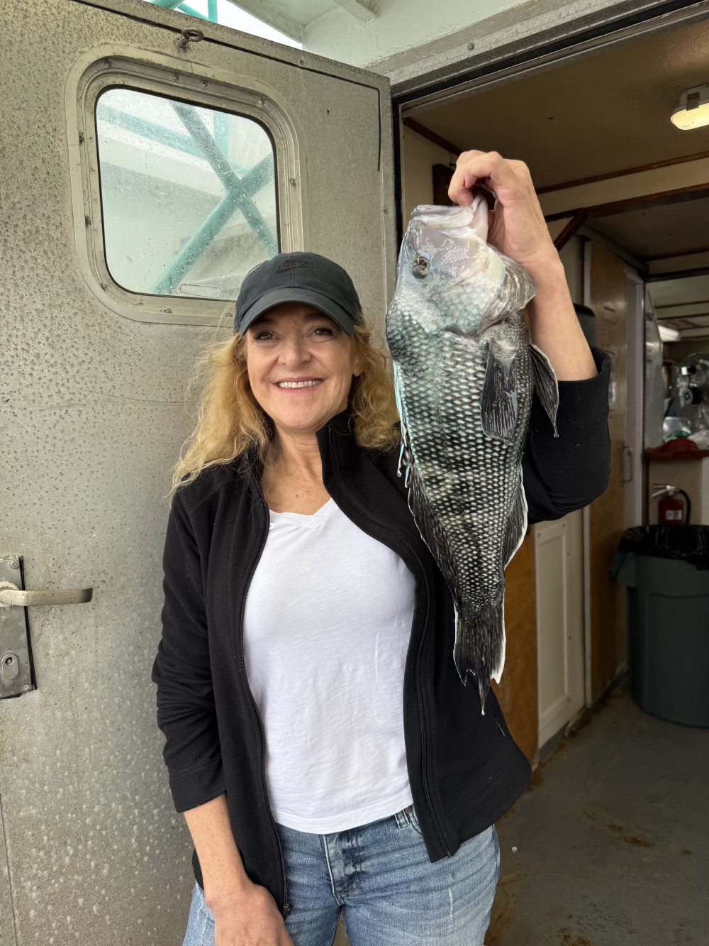 Person holding a large fish inside a boat cabin.