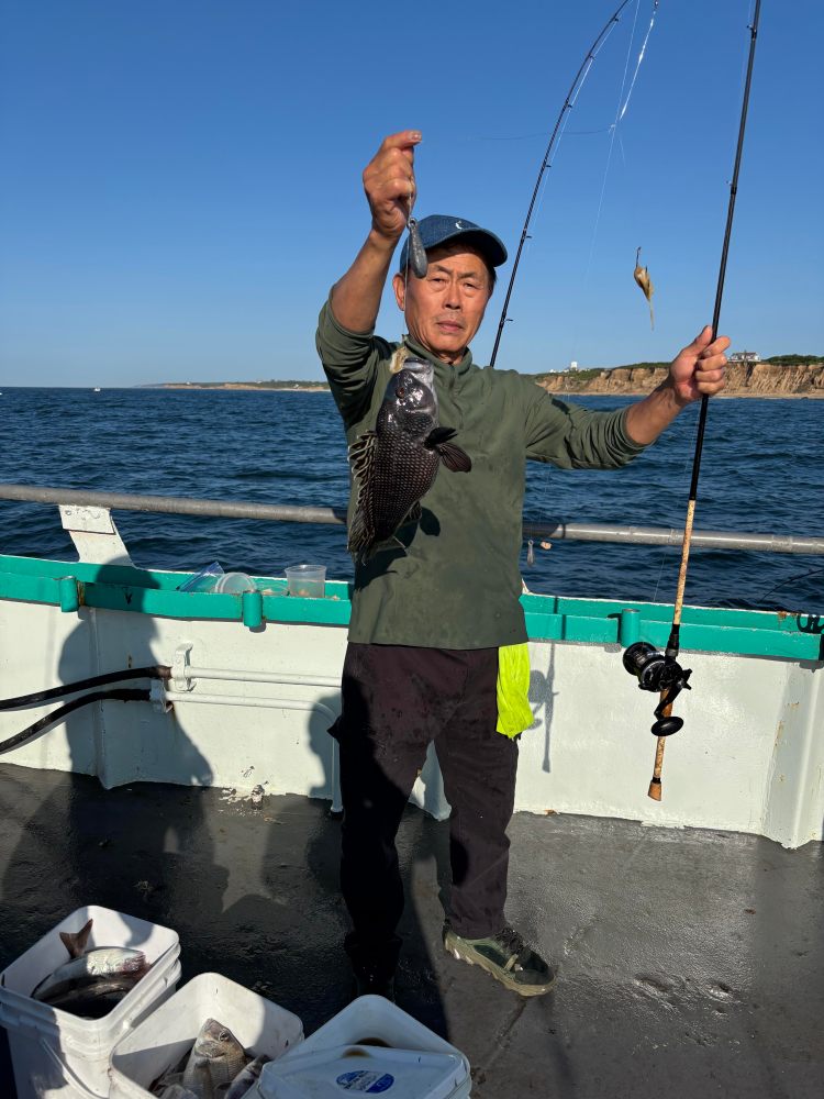 Person holding a fish on a boat with fishing rod, sea in background.