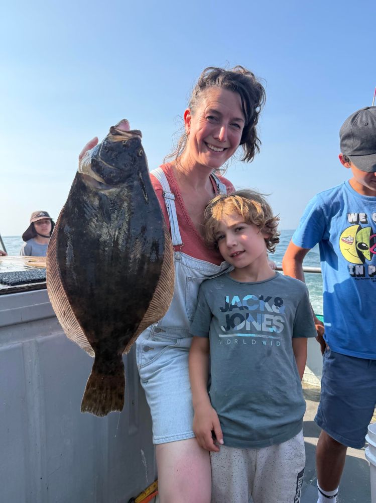 Woman holding a large fish next to a child on a boat.