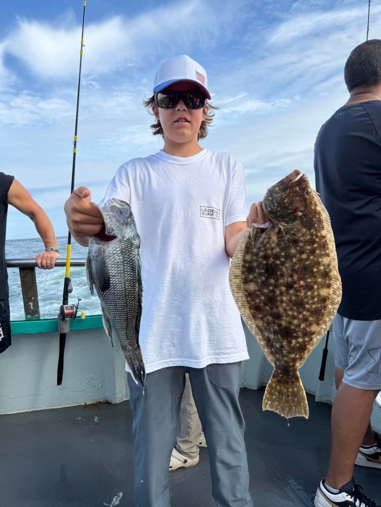 Person holding two fish on a boat deck.