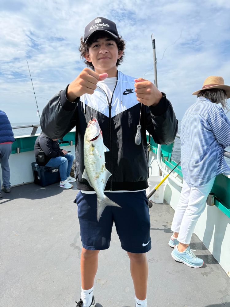 Person holding a fish on a boat deck with others in the background.