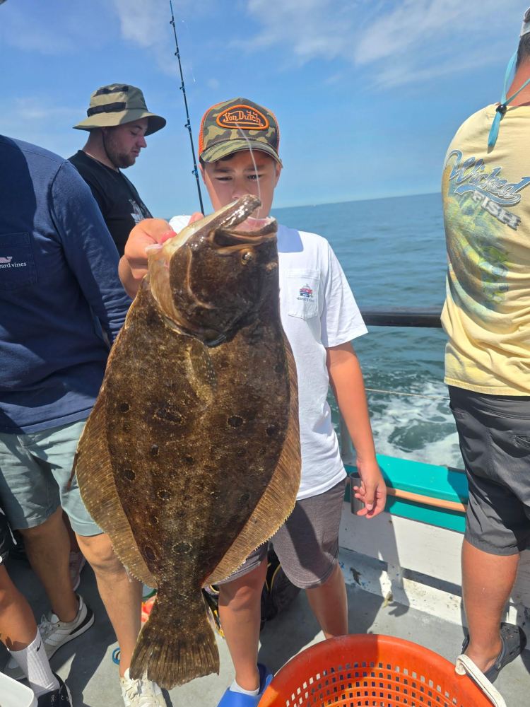 Person on boat holds large fish with ocean in background.