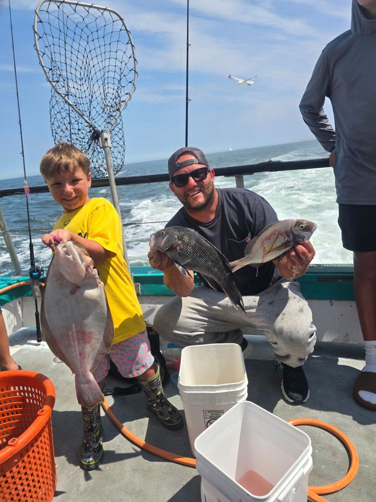 Child and adult holding fish on a boat with ocean in background.