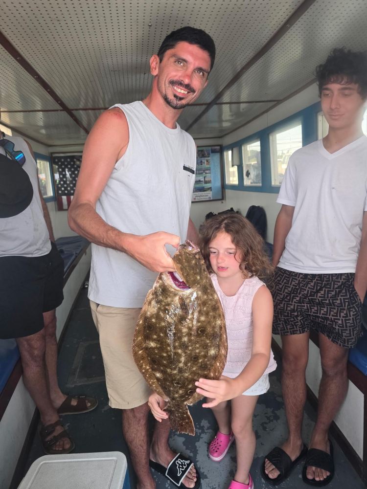 Man and child holding a large fish on a boat, with people watching.