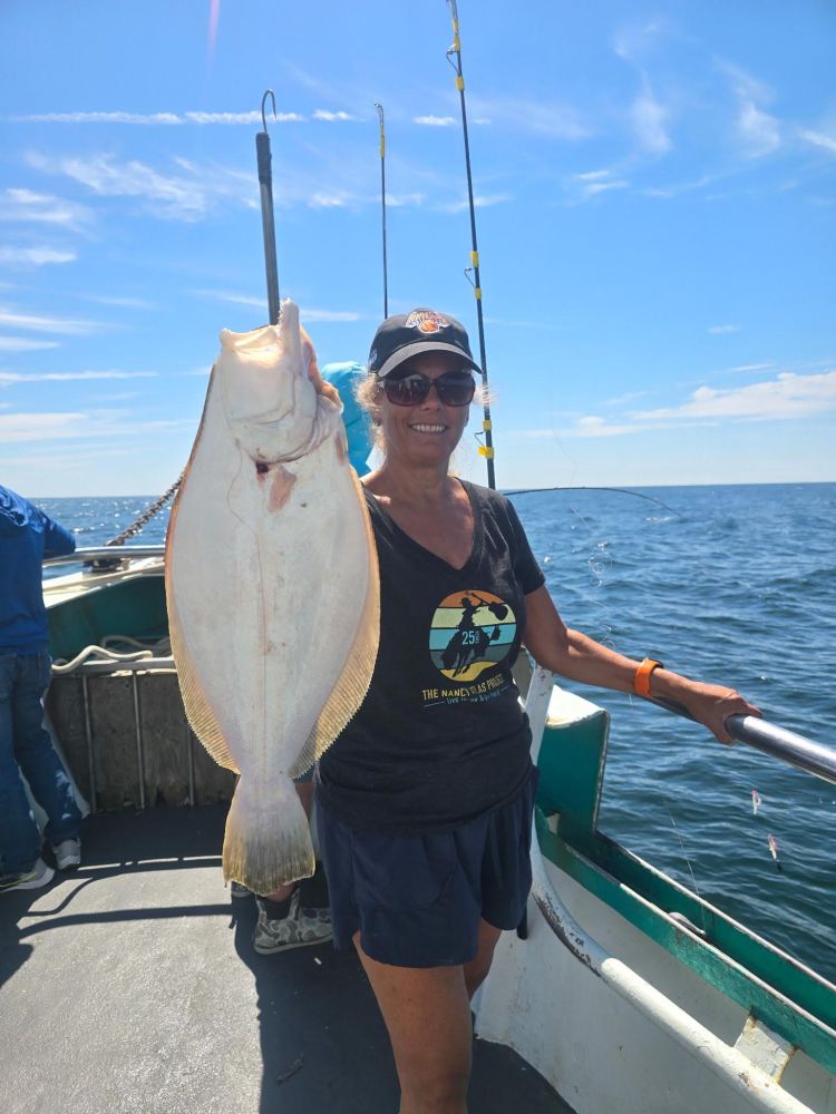 Person holding a large flat fish on a boat with ocean in the background.
