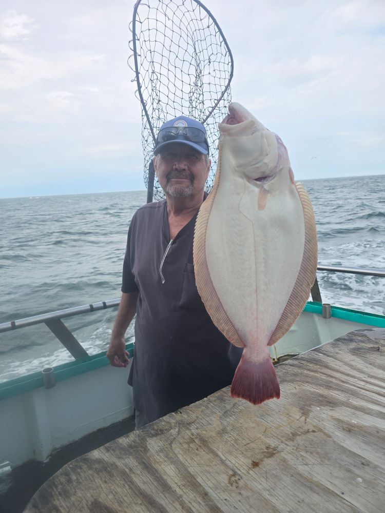 Man holding a fish on a boat with a net in the background.