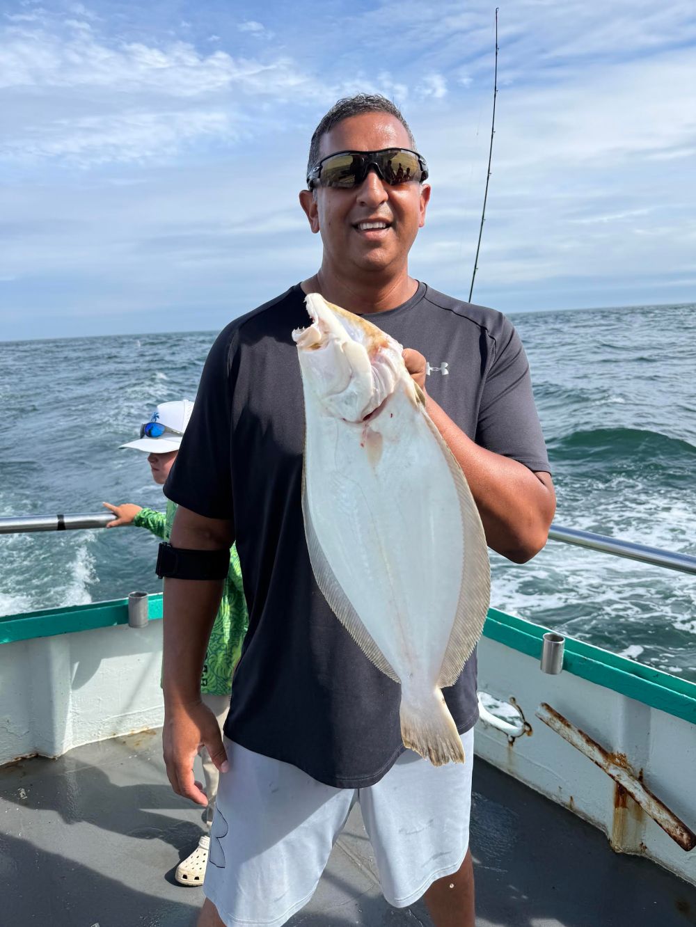 Man holding a large fish on a boat at sea.