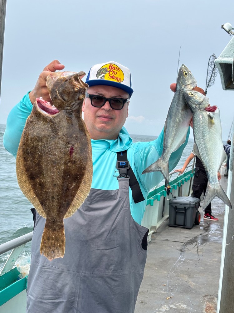 Person holding a flat fish and two silver fish on a boat deck.