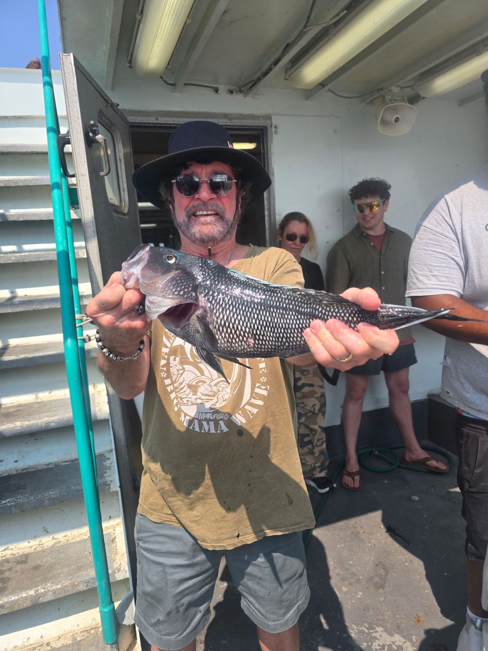 Person holding a fish on a boat in sunny weather.
