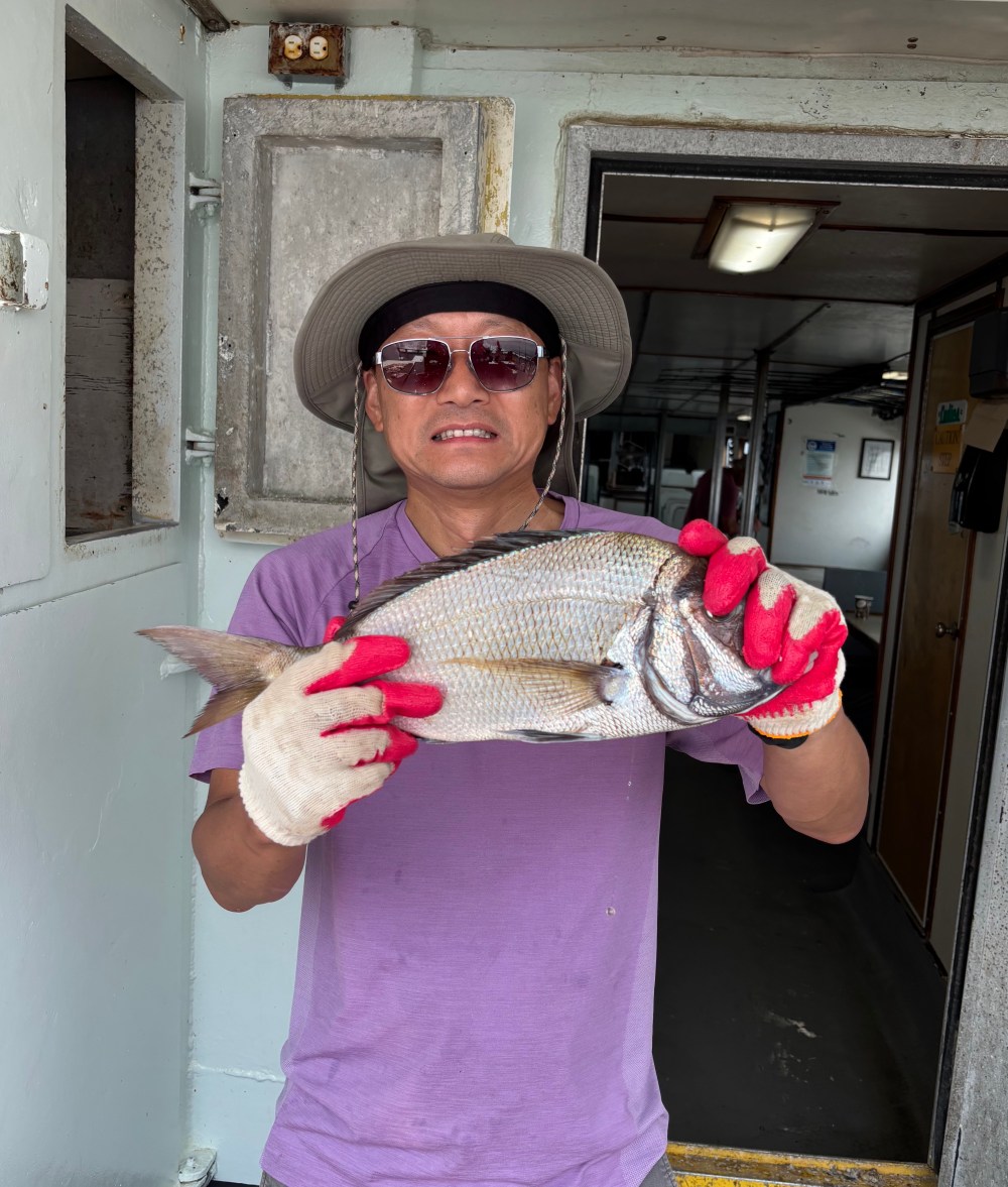 Person wearing hat and gloves holding a large fish indoors