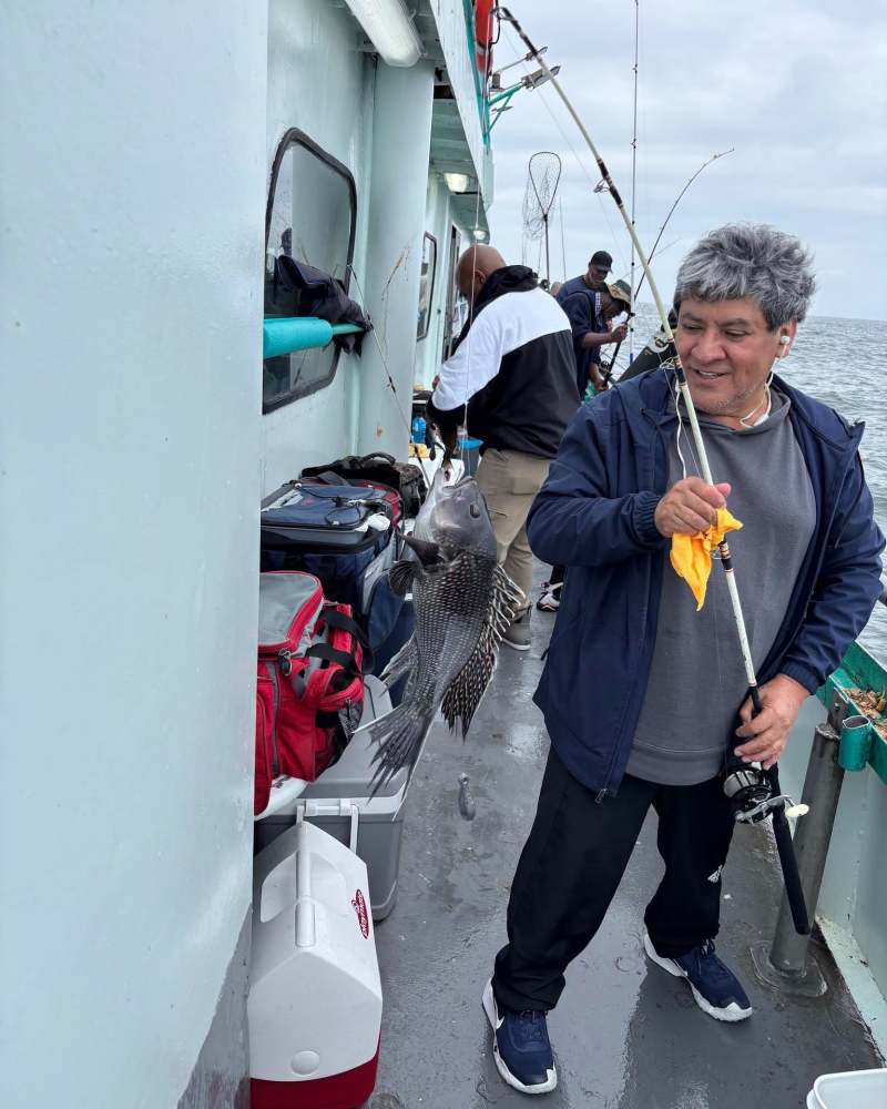 Person holding a fish on a boat with fishing gear.