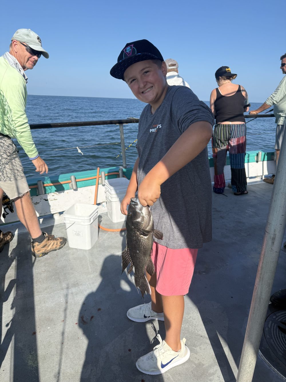Person on a boat holds a fish, with ocean in the background.