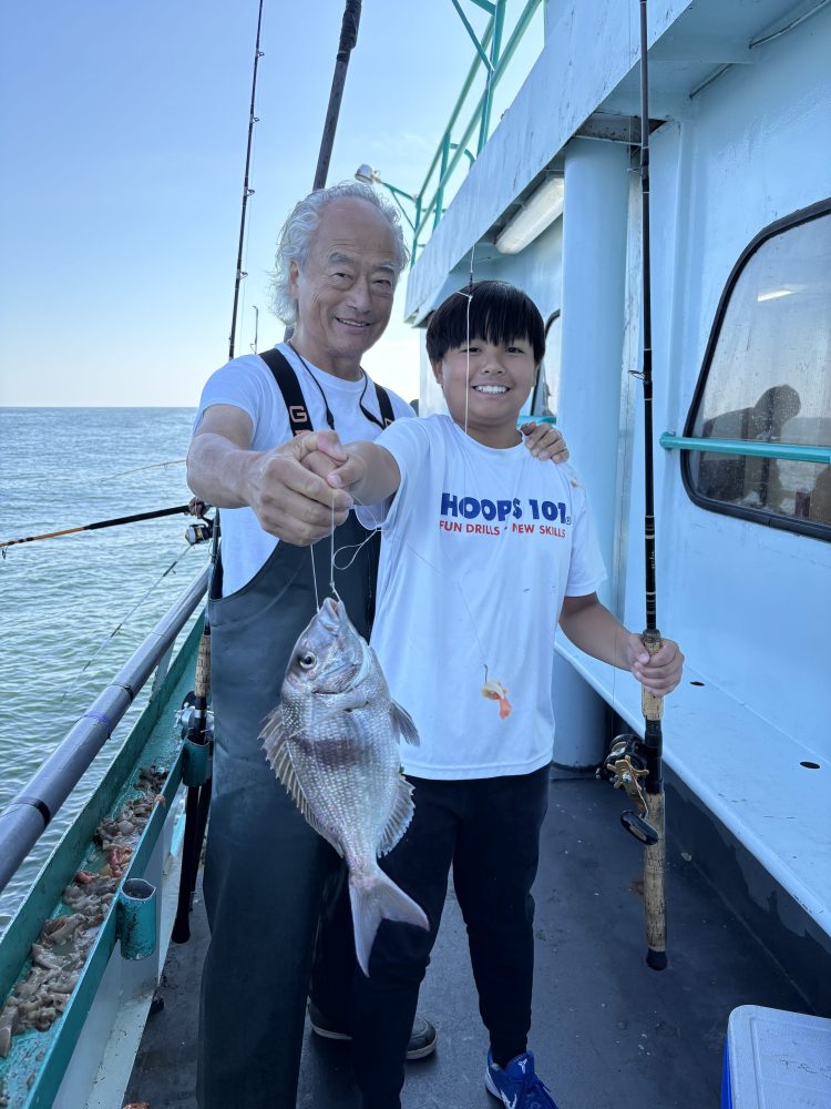 Two people on a boat holding a caught fish.