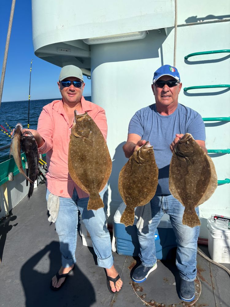 Two people holding freshly caught fish on a boat.
