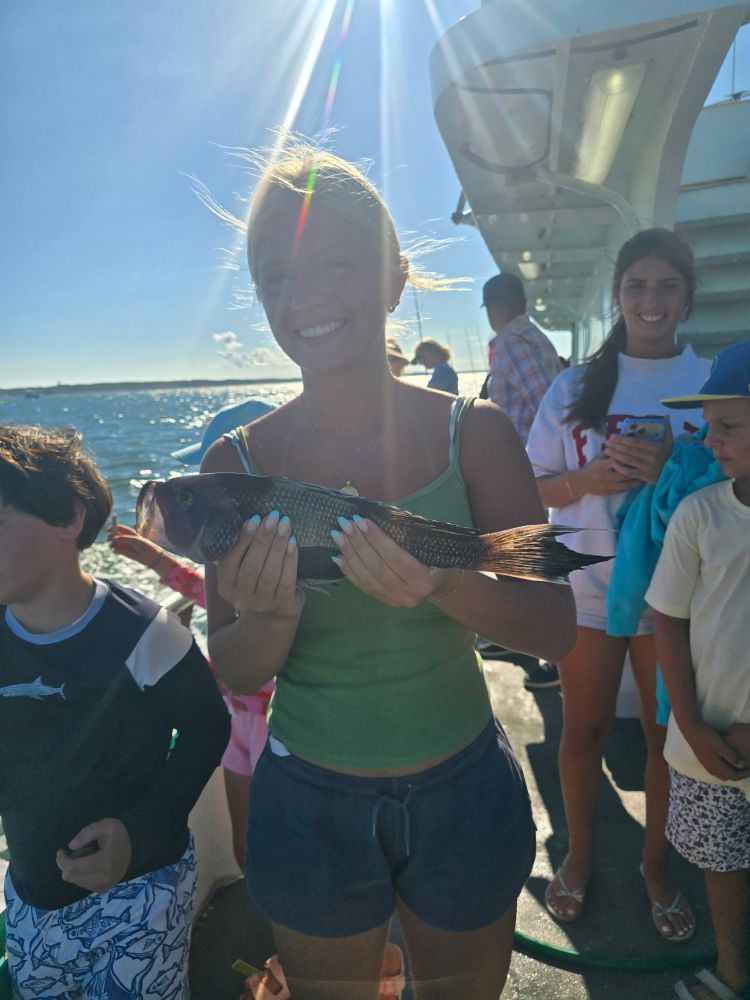 Person holding a fish on a boat with others in the background.