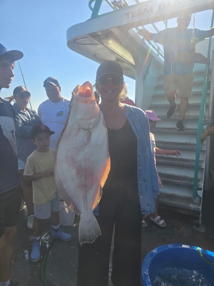 Person holding large fish on a boat, surrounded by onlookers.