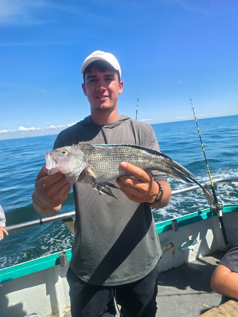 Person holding a fish on a boat with ocean in background.
