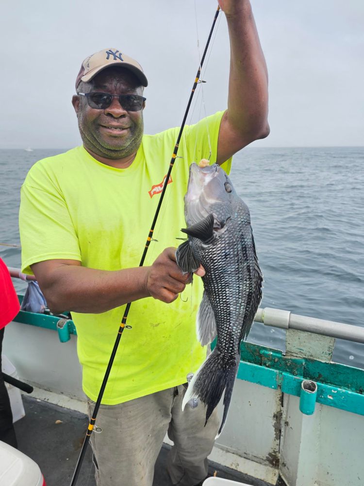 Man on a boat holding a fishing rod with a large fish.