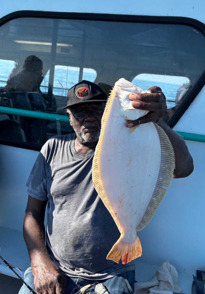 Man holding a large flat white fish on a boat.