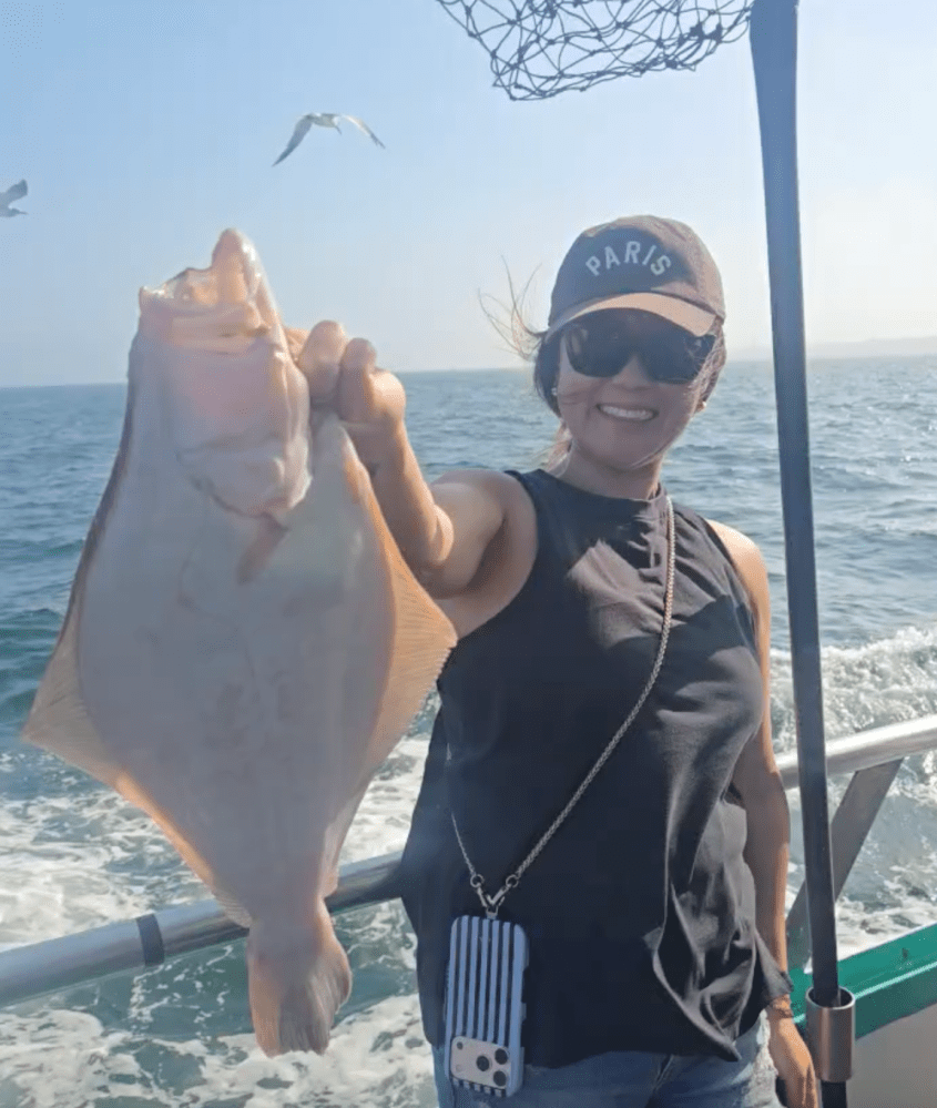 Person holding a large fish on a boat with seagulls flying in the background.