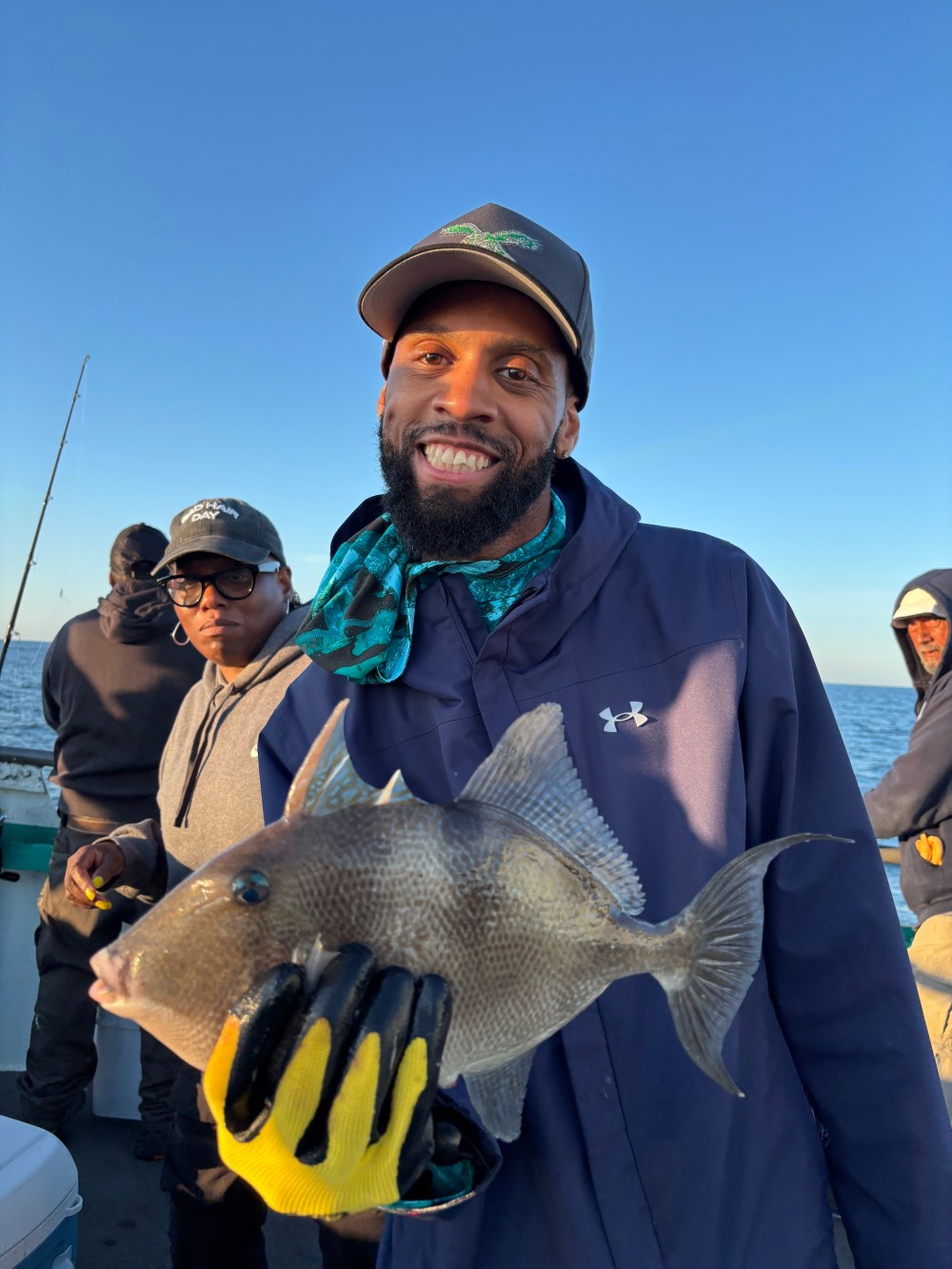 Man smiling on a boat holding a fish, others in background.