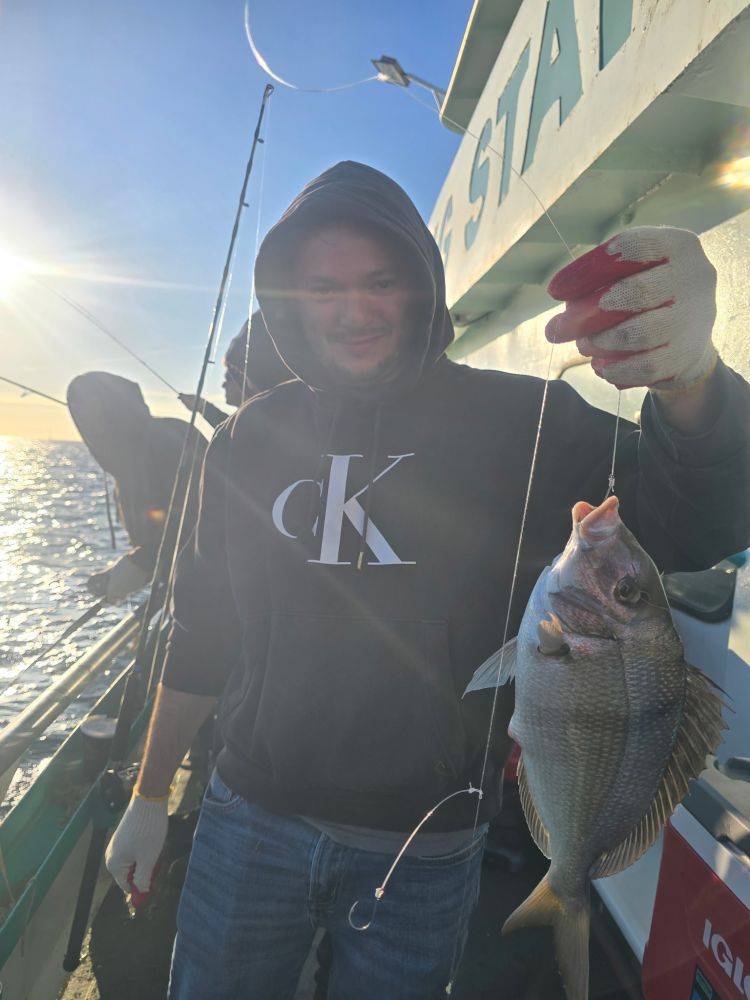 Person on a boat holding a caught fish with fishing gear.