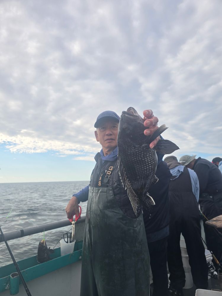 Person on boat holding a large fish against a cloudy sky.