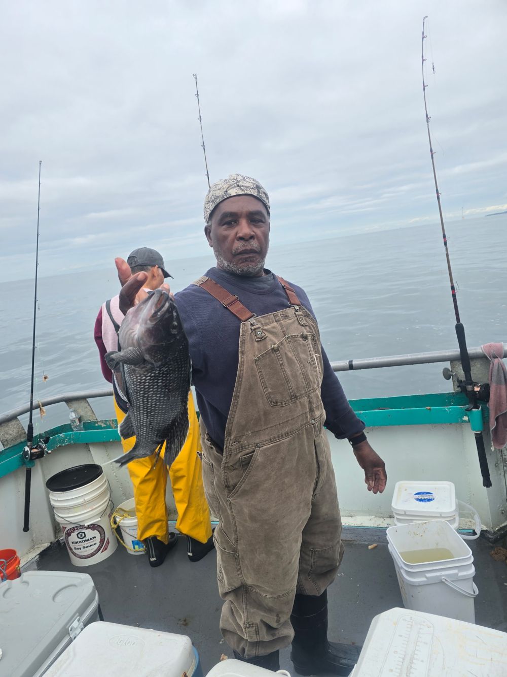 Man holding a fish on a boat with fishing gear visible.