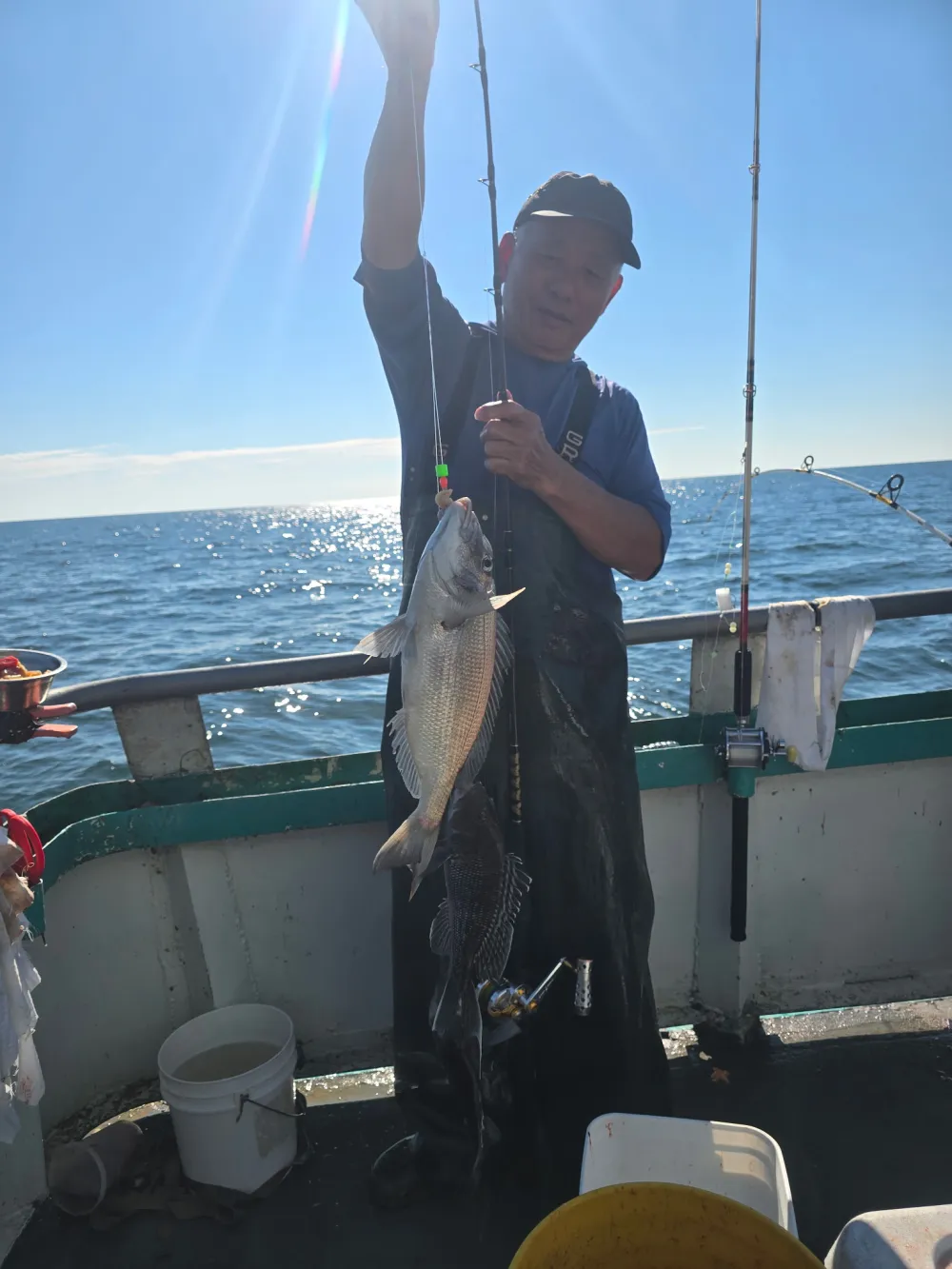 Person holding a fish on a boat under clear sky.