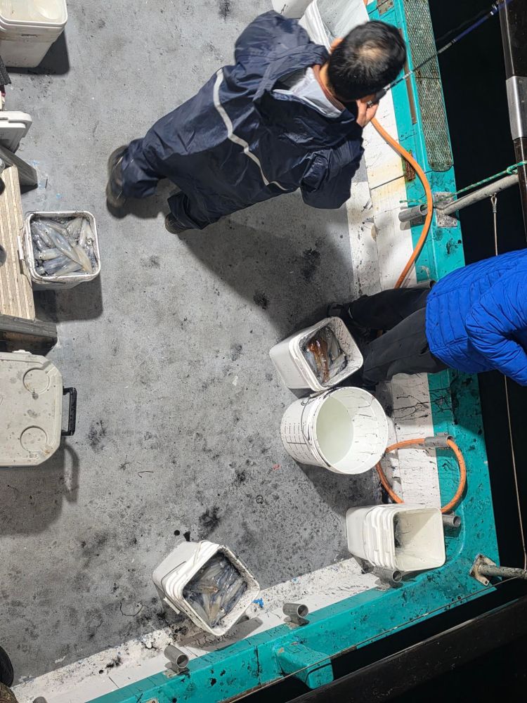 Two people on a boat deck with buckets and supplies.