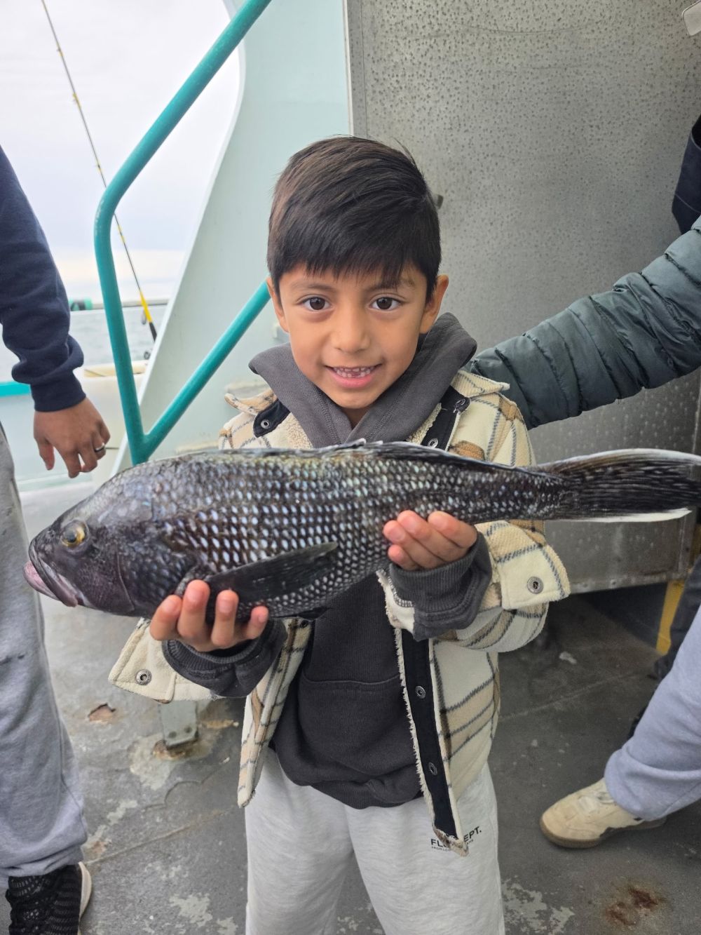 Child holding a large fish on a boat deck.