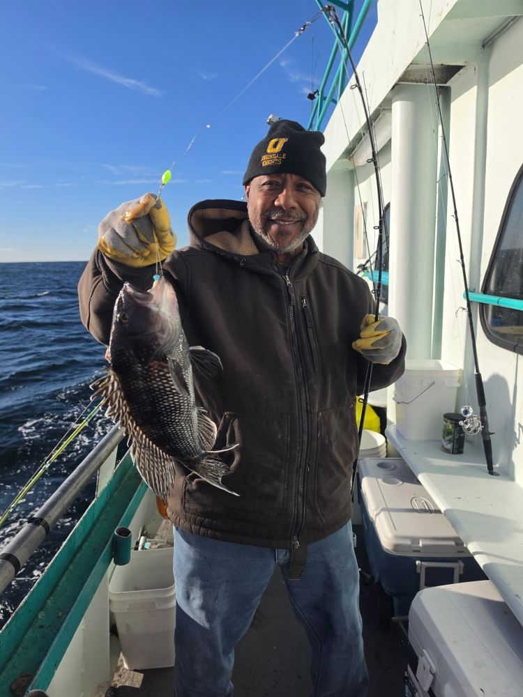 Smiling person on a boat holding a fish on a fishing line.