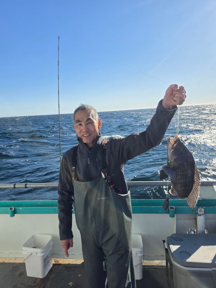 Person holding a fish on a boat with ocean in the background.