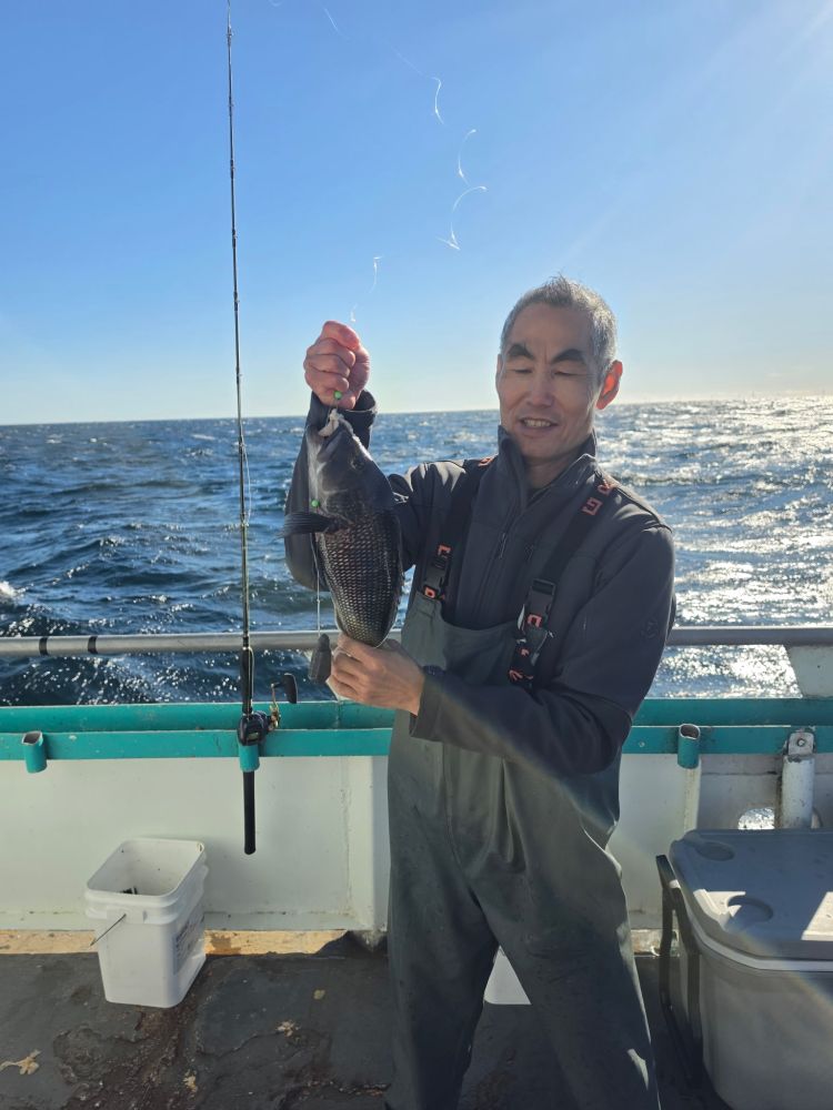 Person holding a fish on a boat with ocean in the background.